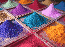 A variety of coloured pigments separated by hollow, shallow, wooden bins, layered into piles of differing heights and stability.
